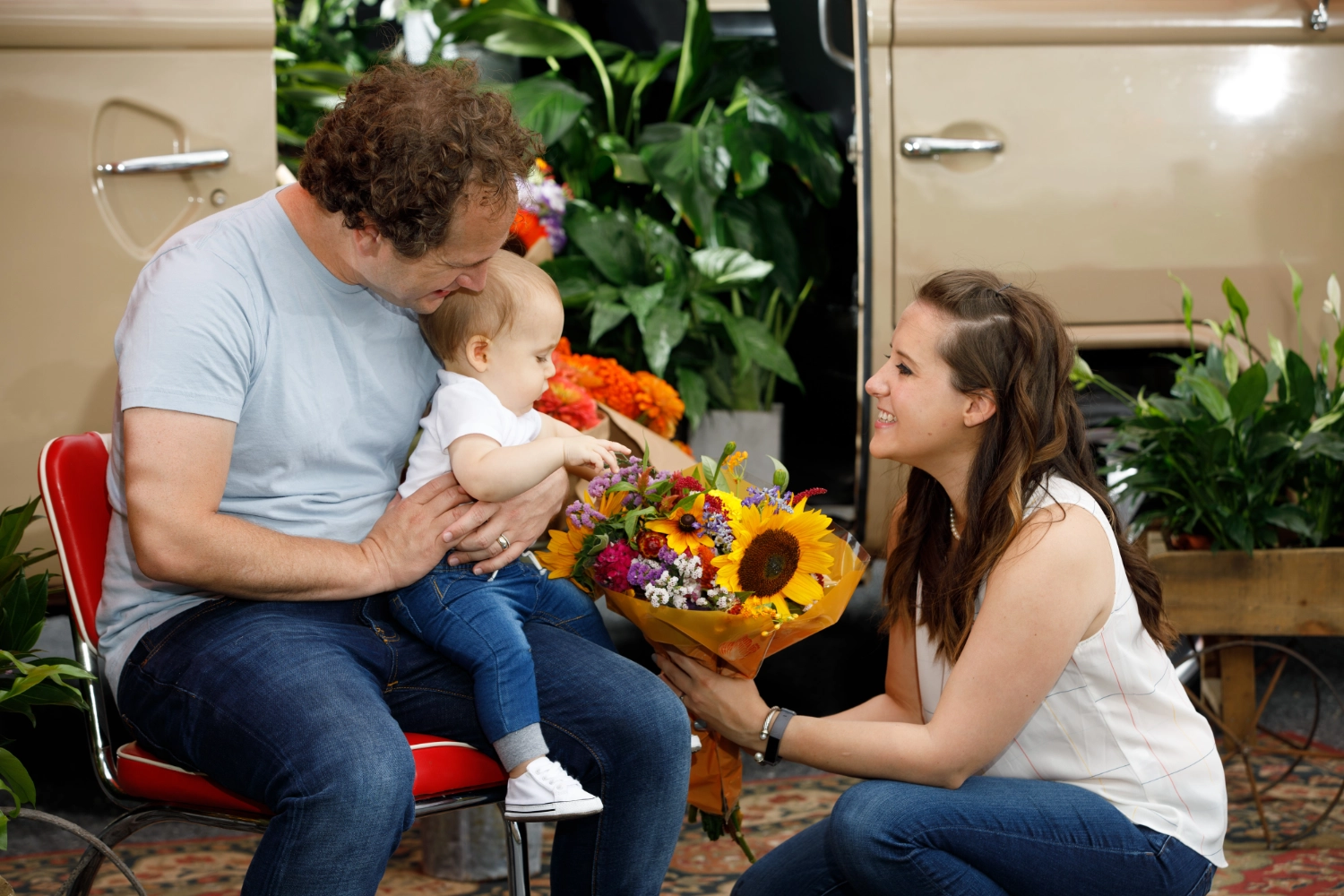 Guests gathered with a fresh bouquet beside the VW Blooming Bus amid potted greenery