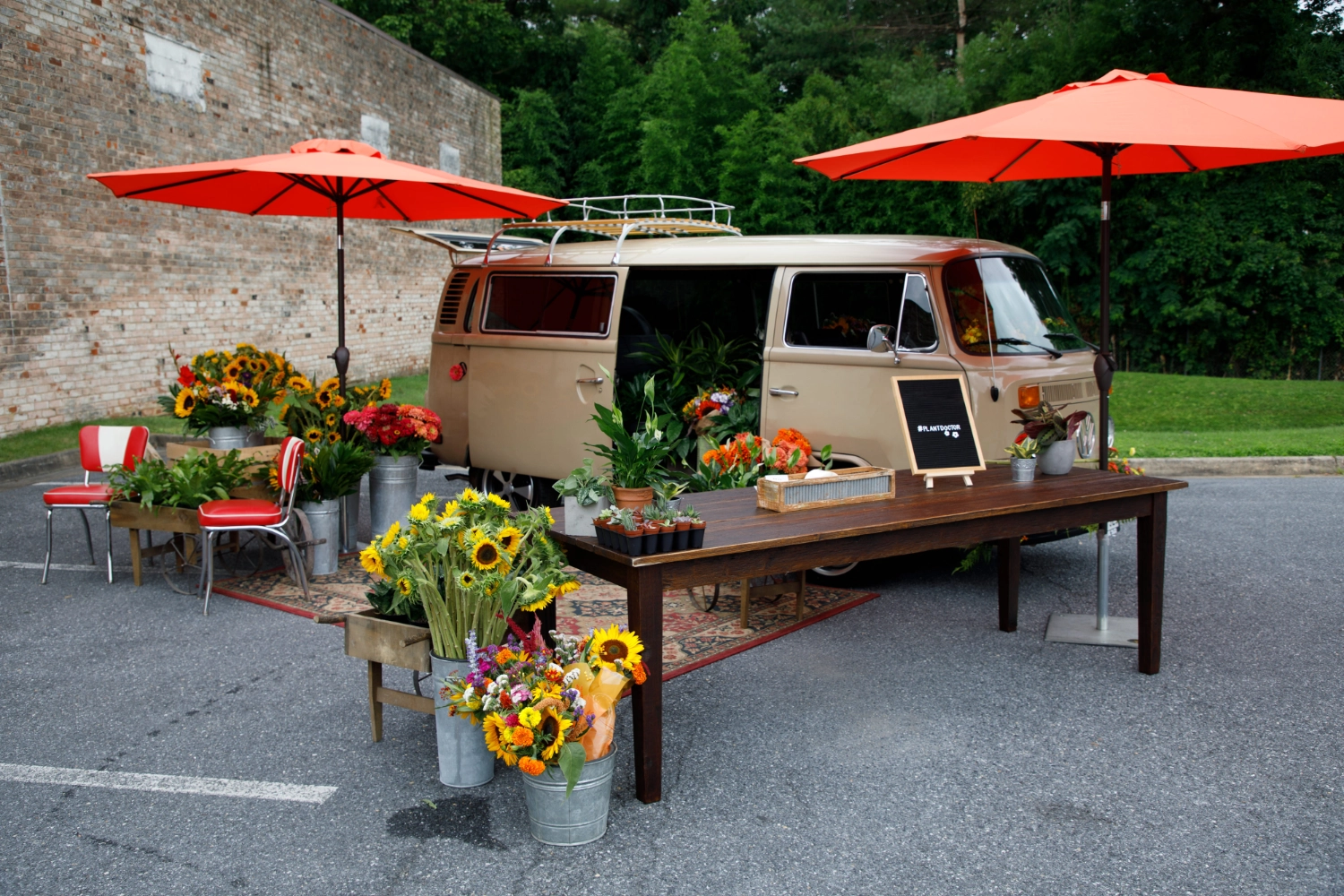 The VW Blooming Bus set up as a pop-up flower bar with red umbrellas and buckets of fresh seasonal stems